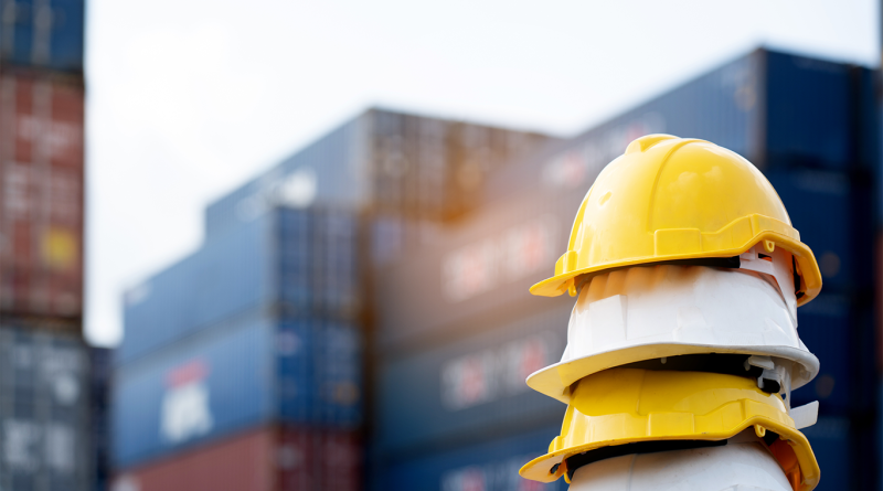 Three hardhats sat in a row in front of warehouse to support steelwork firm article