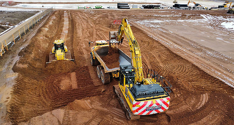 an excavator loading soil into a dumper truck at a construction site