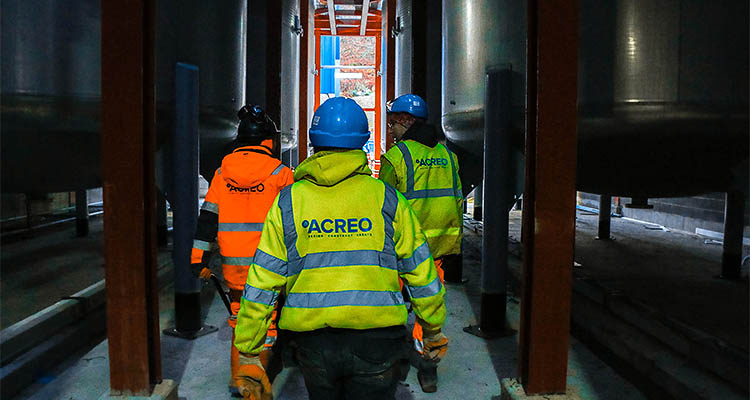 workers wearing high-visibility vests with the logo "ACREO" printed on the back