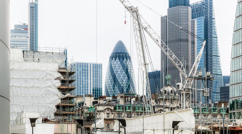 Idle UK construction site with cranes and incomplete buildings under cloudy skies, representing slowdown in building activity