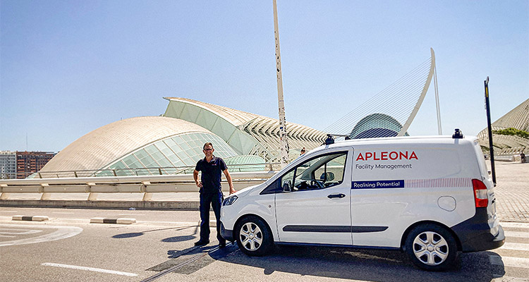 a man standing next to a white van with the Apleona logo and text.