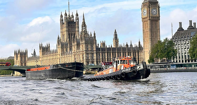 a tugboat named GPSVINDIN pulling a barge on the River Thames