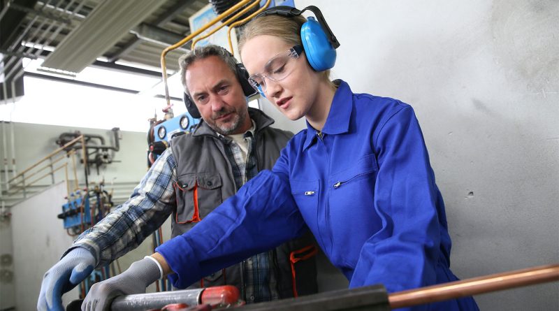 Two plumbing apprentices at a training centre working on low-carbon heating systems, representing Scotland's updated apprenticeship programme