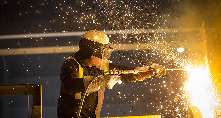 a worker using an oxygen lance to cut or refine steel