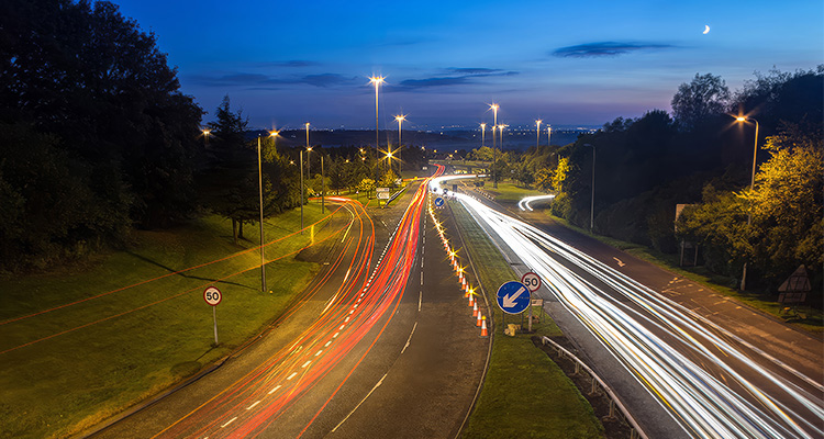 a long-exposure photograph of a busy motorway junction at twilight or night,