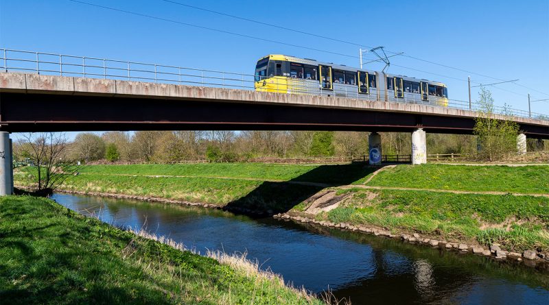 CGI of Preston’s new tram bridge with grey steel arches spanning the River Ribble, supported by two pillars, surrounded by trees