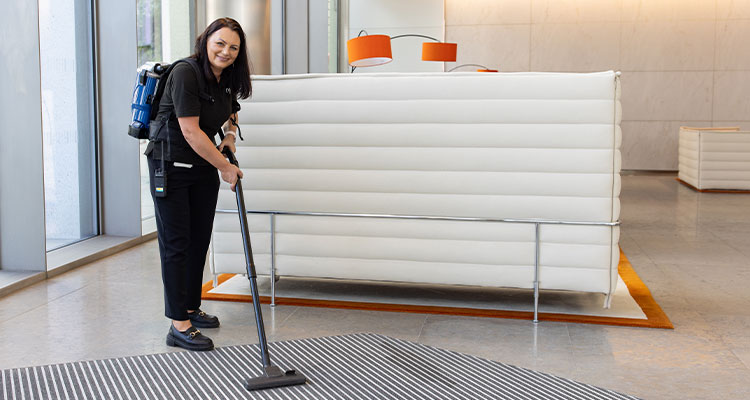 a person using a backpack vacuum cleaner to clean a rug